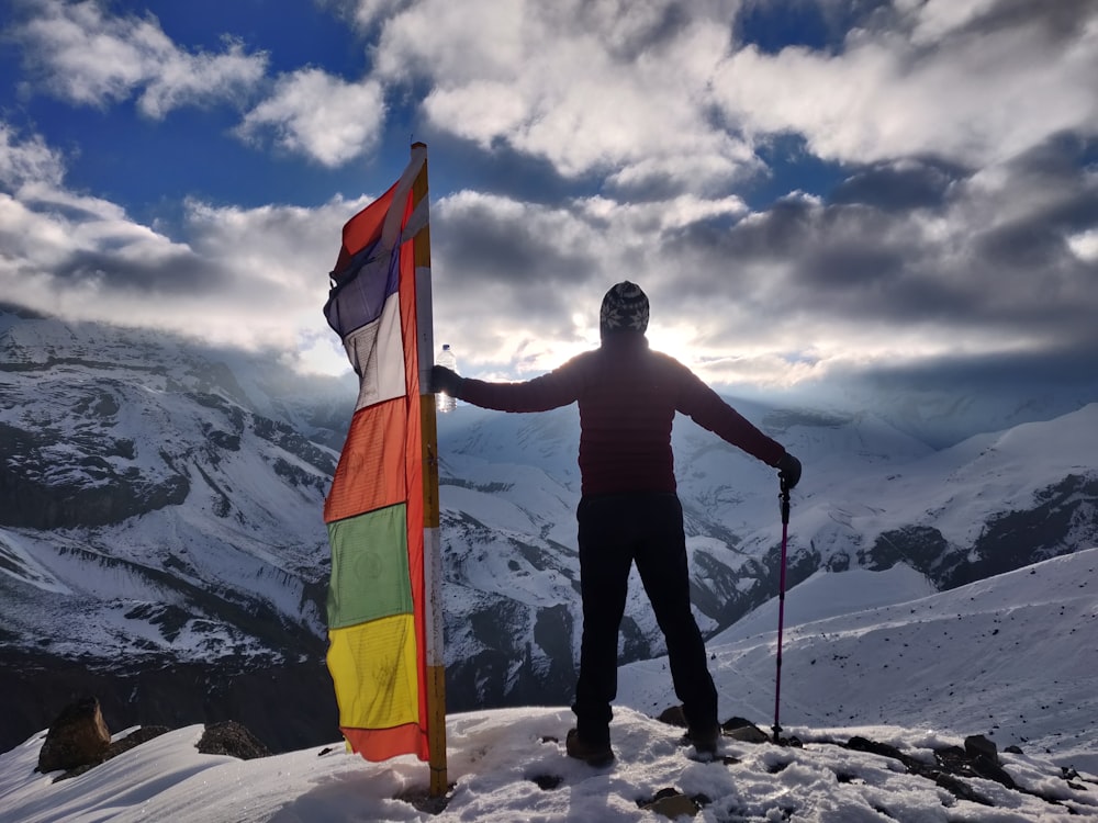 a man standing on top of a snow covered mountain holding a flag