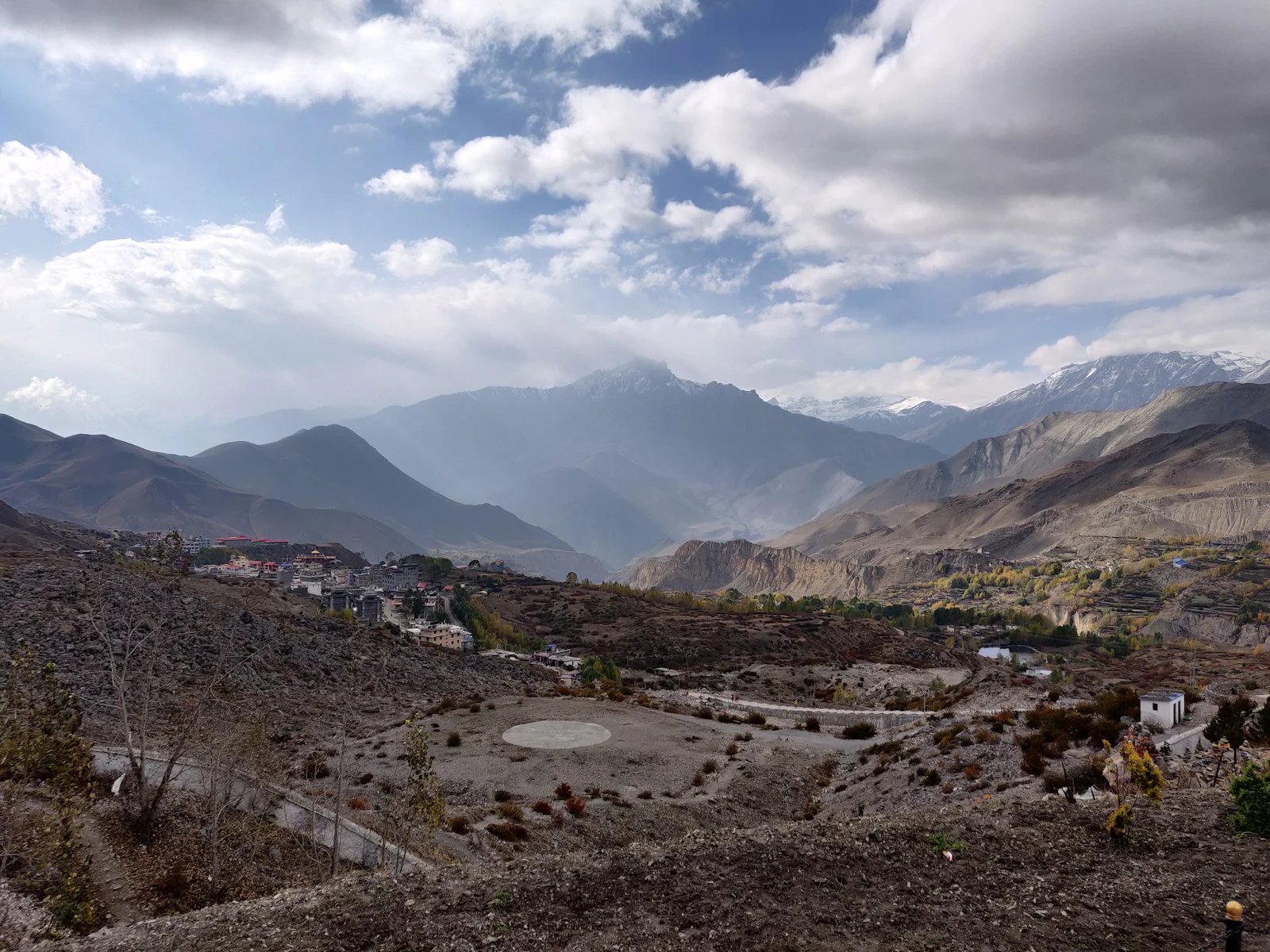 A Mustang village set in a wide valley below hazy Himalayan ranges near Muktinath, Nepal
