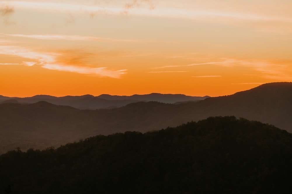 the sun is setting over a mountain range