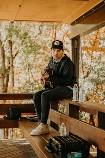 a man sitting on a bench playing a guitar