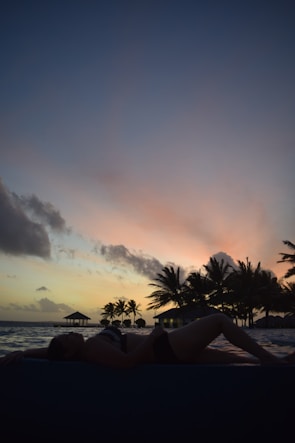 A solo traveler enjoying a serene beach sunset with a backdrop of palm trees.