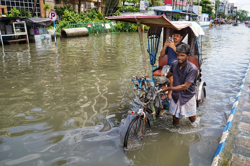 a man standing next to a bike in a flooded street