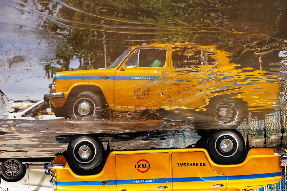 a yellow truck is reflected in a puddle