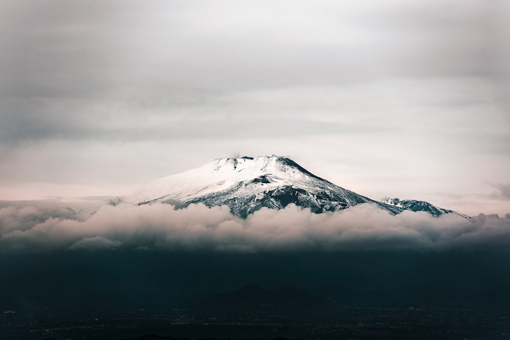 a snow covered mountain in the middle of a cloudy sky