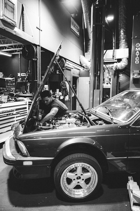 A mechanic working on a car engine in a well-lit garage.