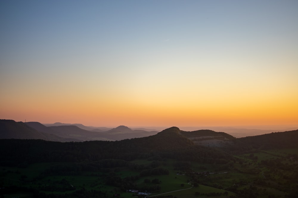 the sun is setting over a mountain range