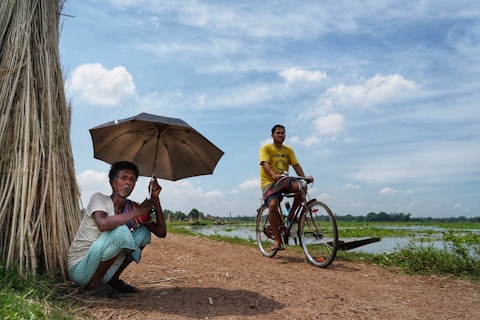 a man sitting next to a tree holding an umbrella