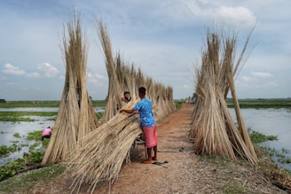 a couple of men standing next to a bunch of sticks