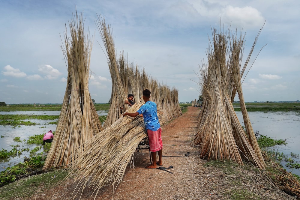 a couple of men standing next to a bunch of sticks