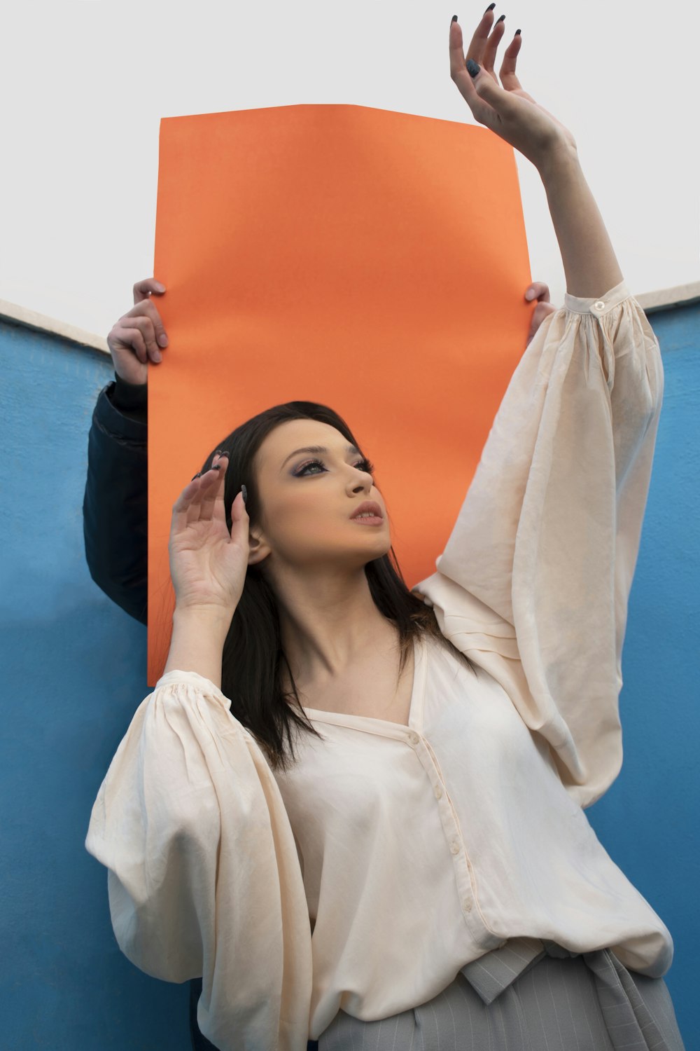 a woman holding up a large orange piece of paper