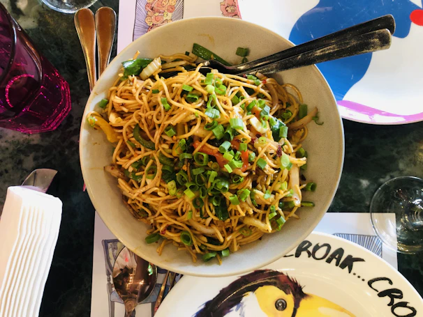 Top view of scallion oil flavor instant noodles garnished with fresh green scallions on a clean blue plate.