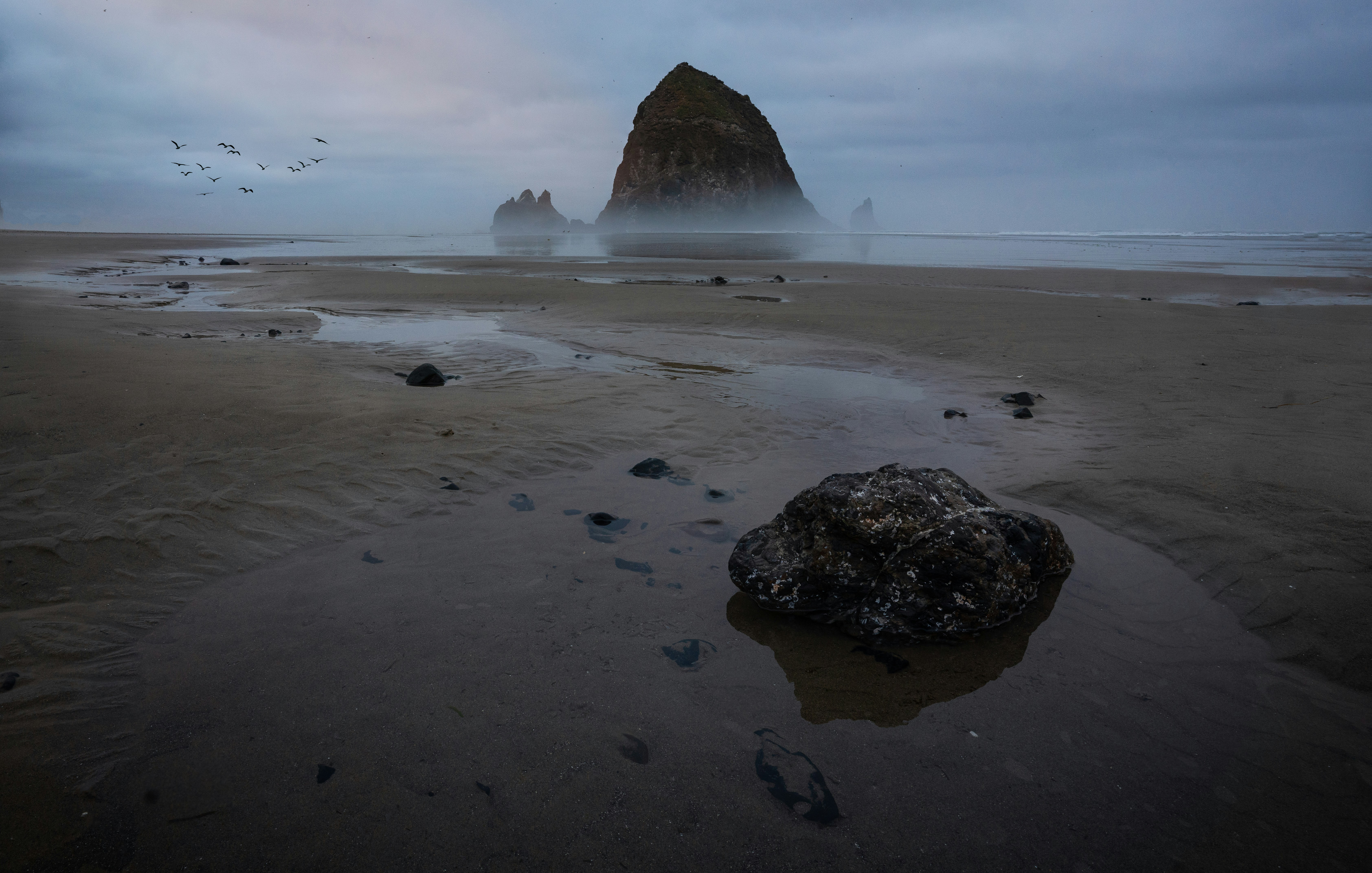 a large rock sitting on top of a sandy beach, Check me out on Instagram! @intricateexplorer