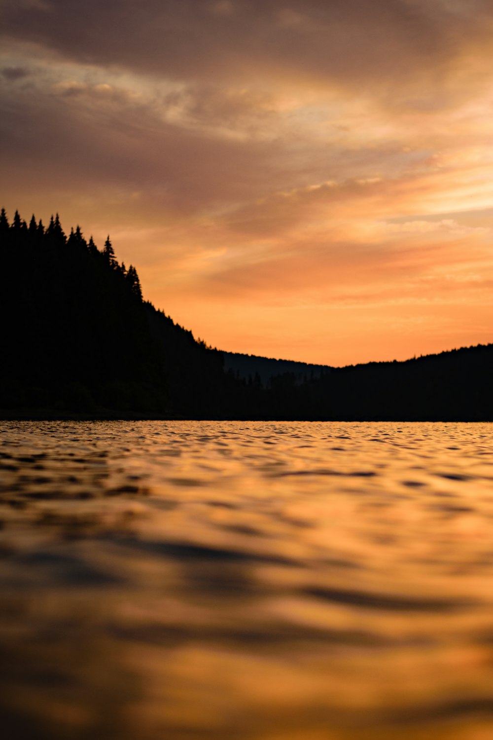 the sun is setting over a lake with a mountain in the background