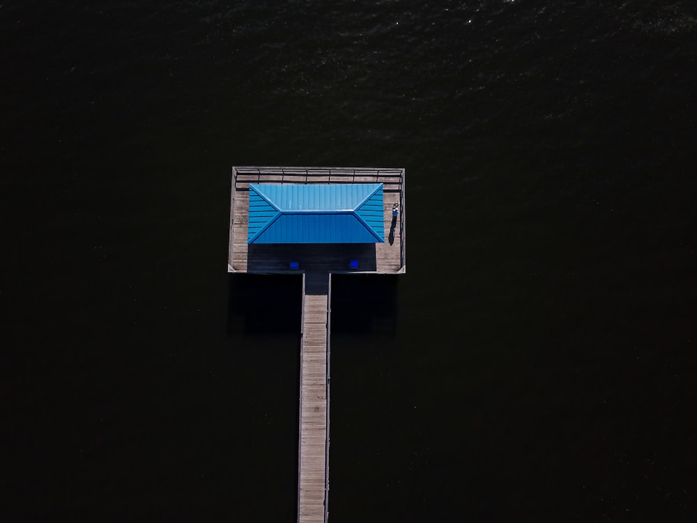 un parapluie bleu assis au sommet d’une jetée en bois