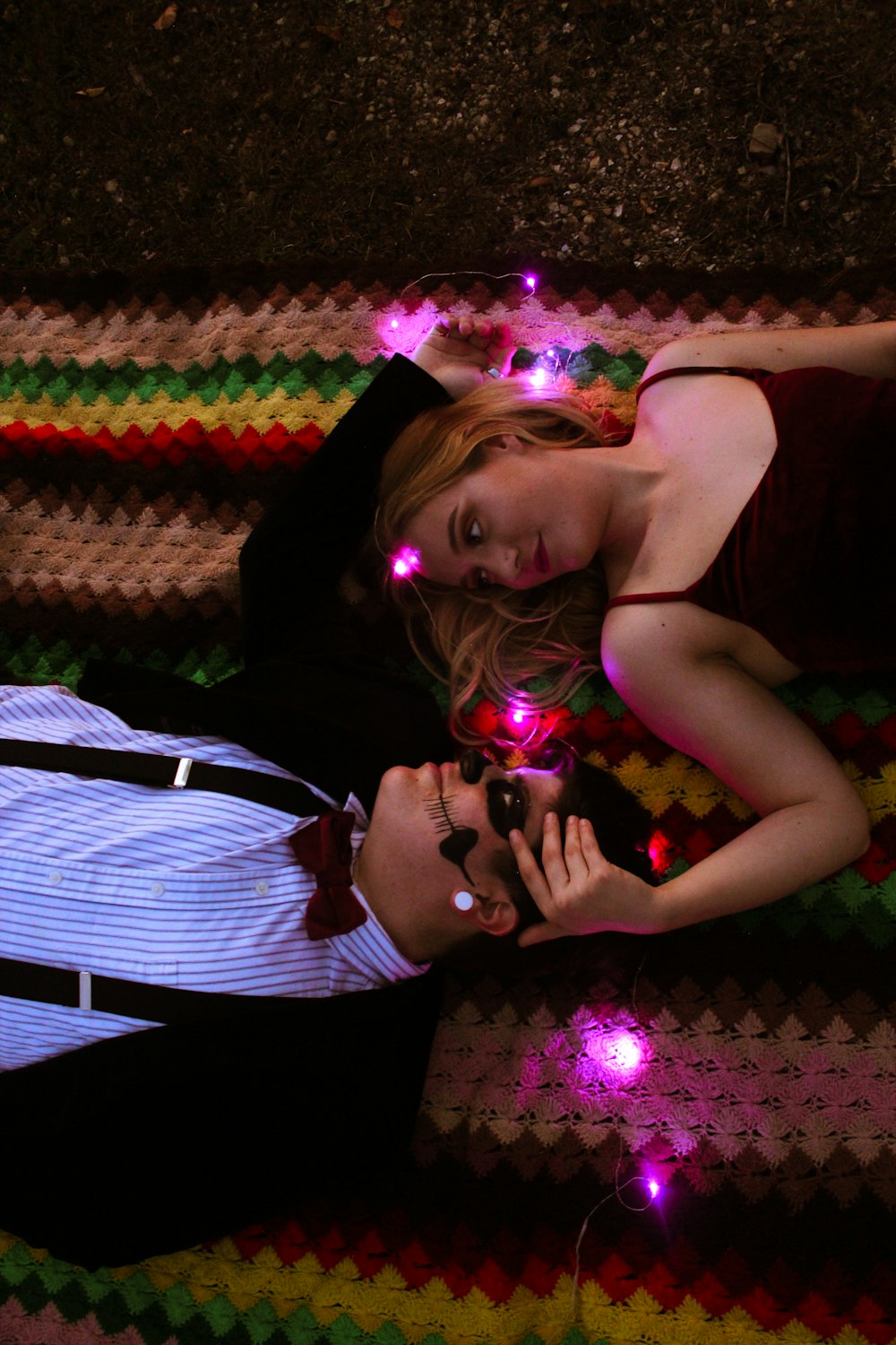 a man and a woman laying on a rug with lights