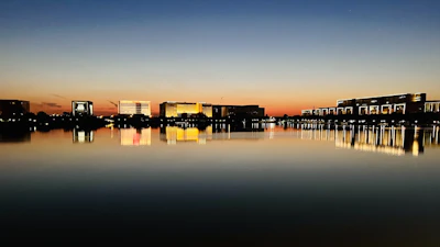 A serene waterfront view at sunset with the Flats Riviera building in the background.