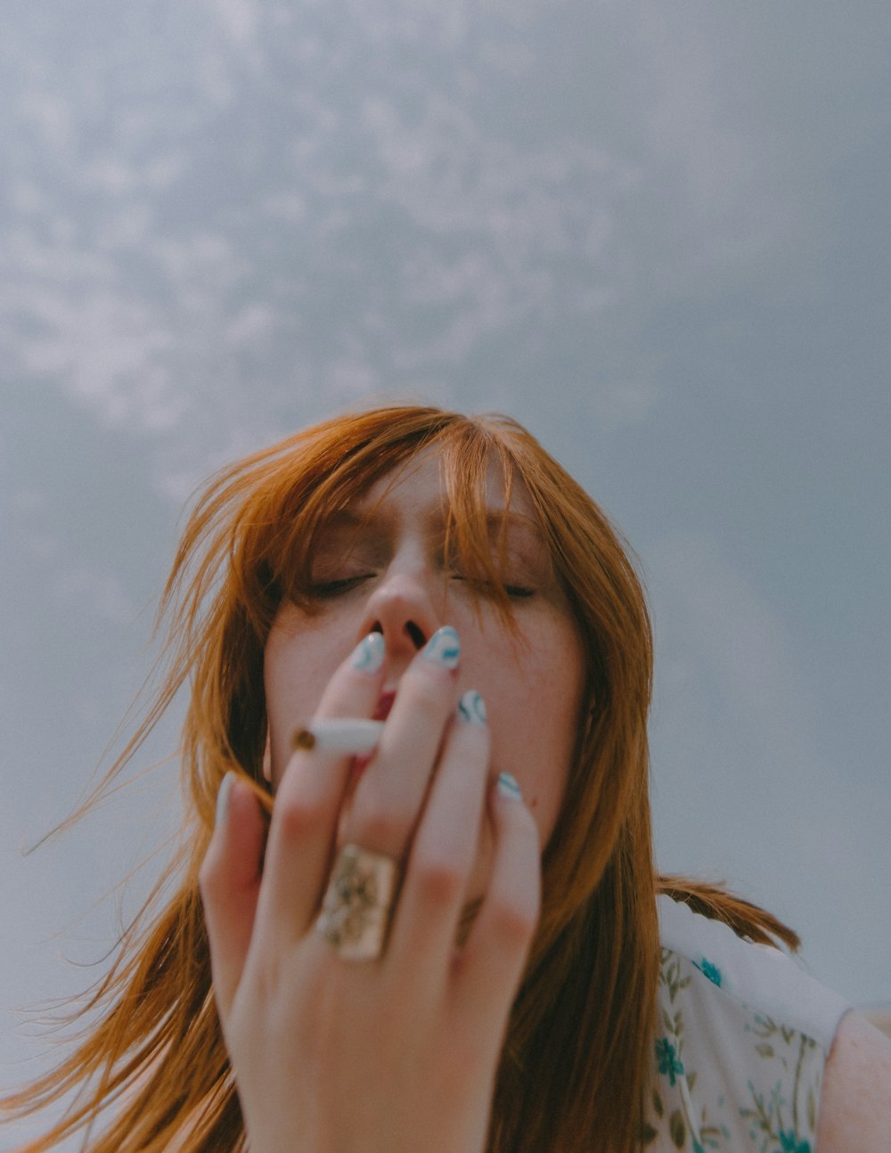 a woman with red hair blowing her hair in the wind