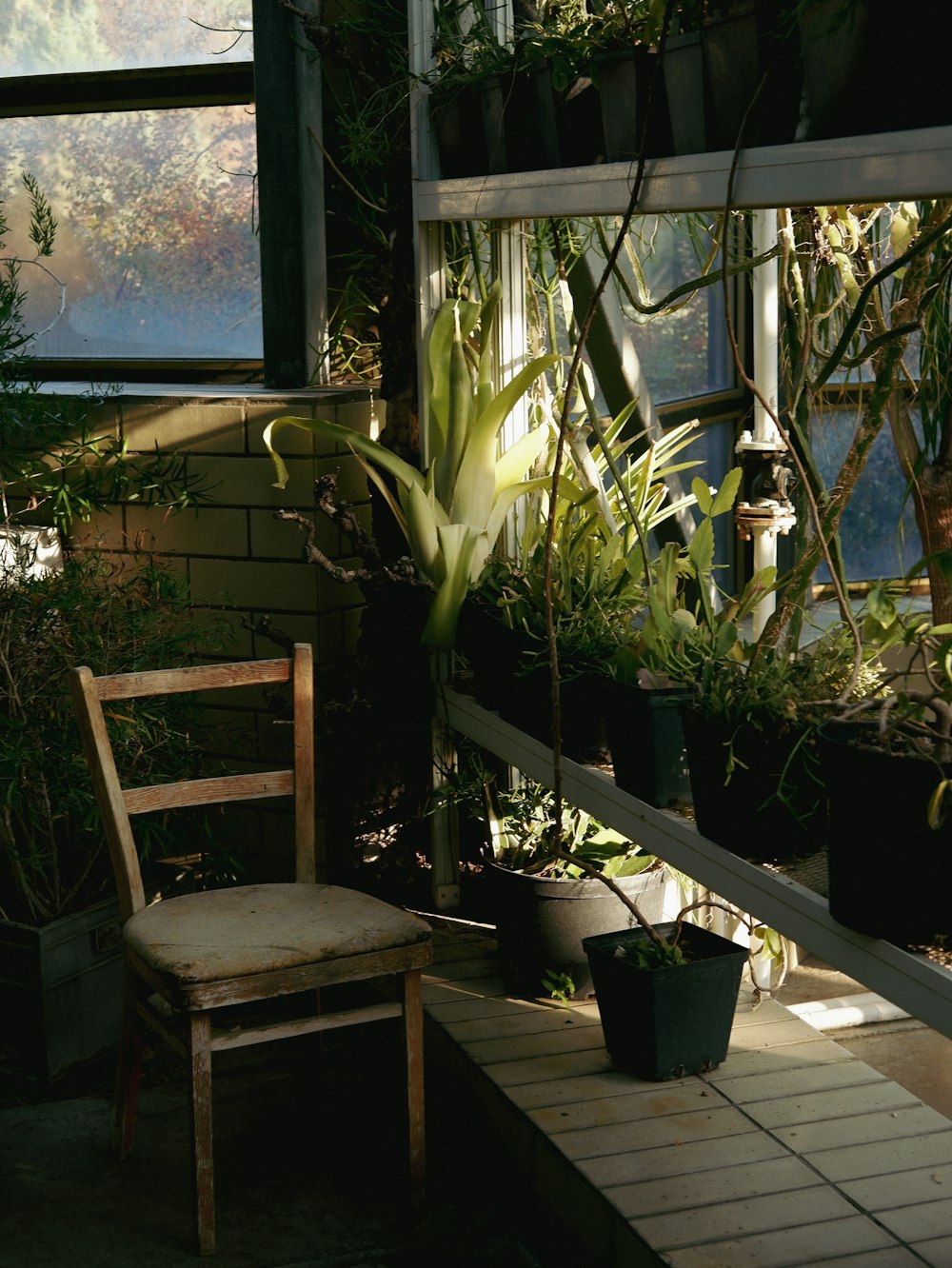 a wooden chair sitting on a porch next to potted plants