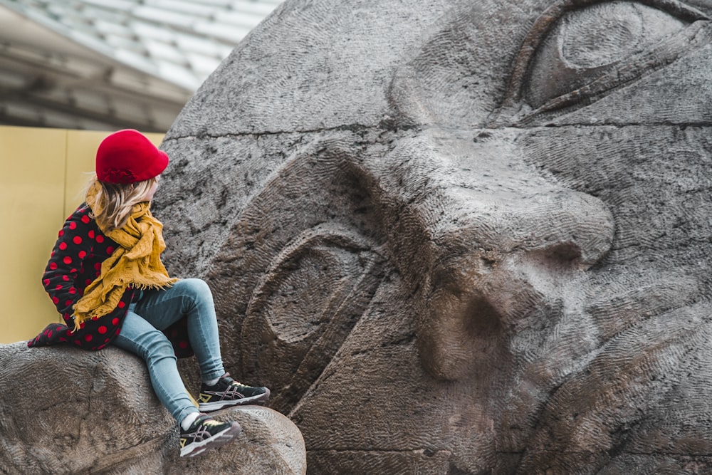uma mulher sentada no topo de uma estátua de pedra