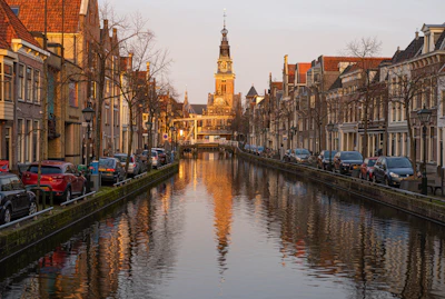 Colorful houses lining the canals of Amsterdam during golden hour, with bicycles parked along the water’s edge.