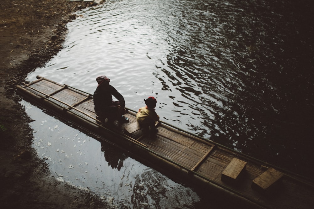 a couple of people sitting on top of a wooden raft