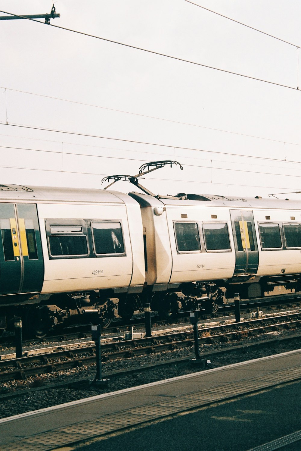 a white train traveling down train tracks next to a loading platform