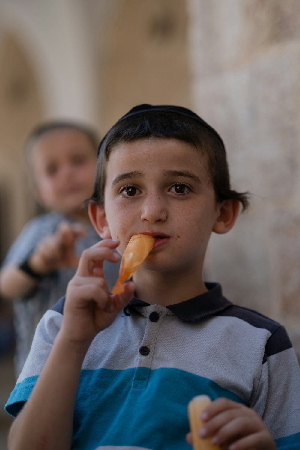 a young boy holding a piece of food in his mouth