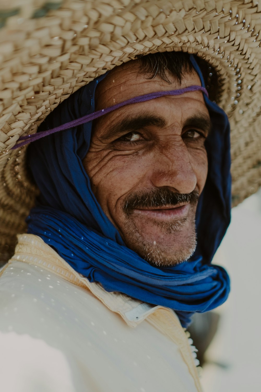 a man wearing a straw hat and blue scarf