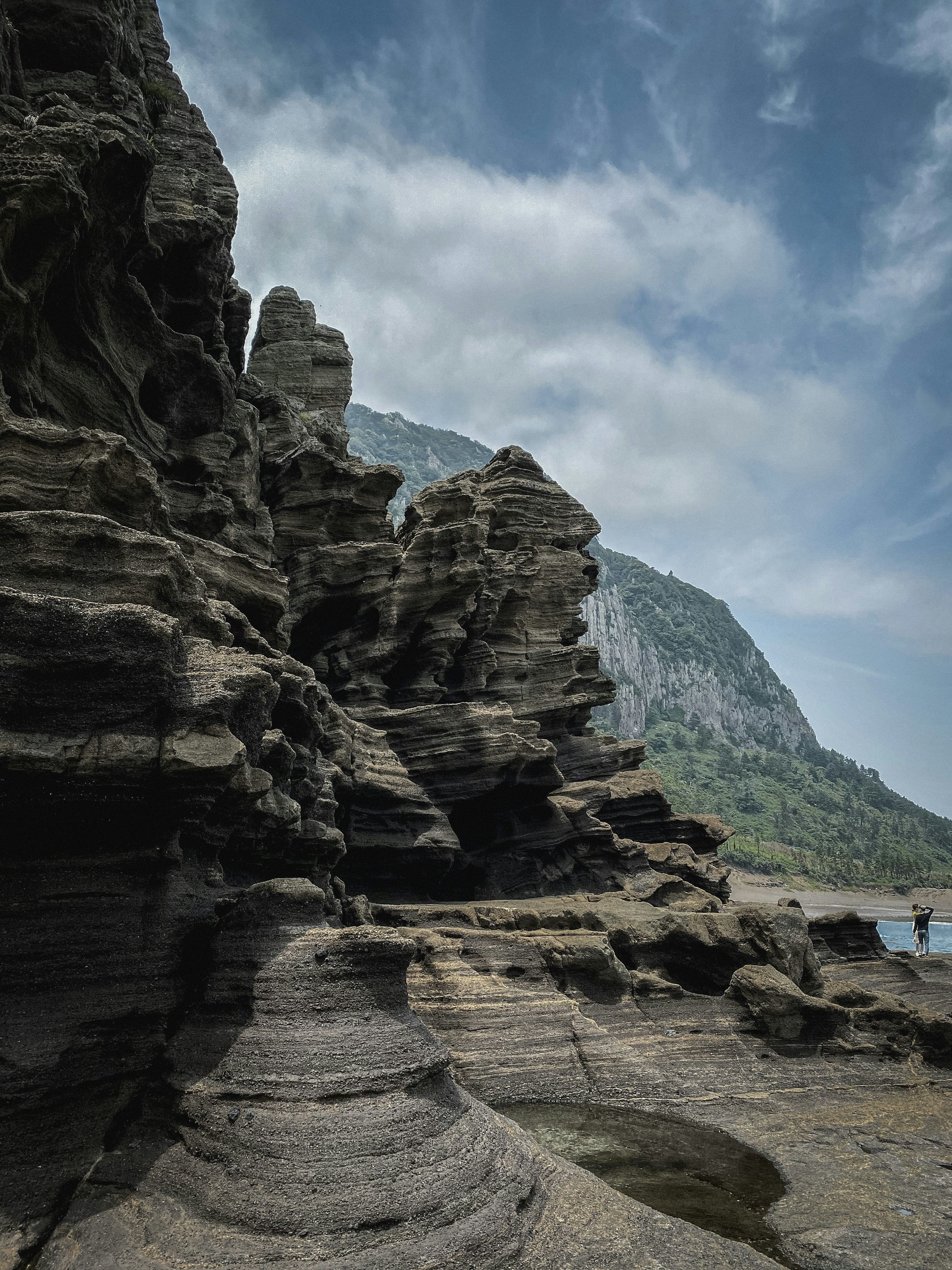 a person standing on a rocky beach next to a body of water