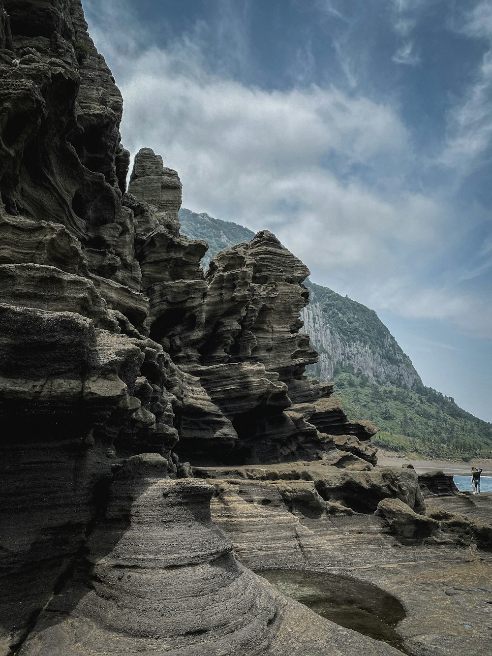 a person standing on a rocky beach next to a body of water