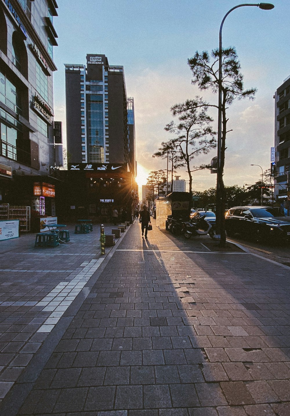 a person walking down a sidewalk next to tall buildings