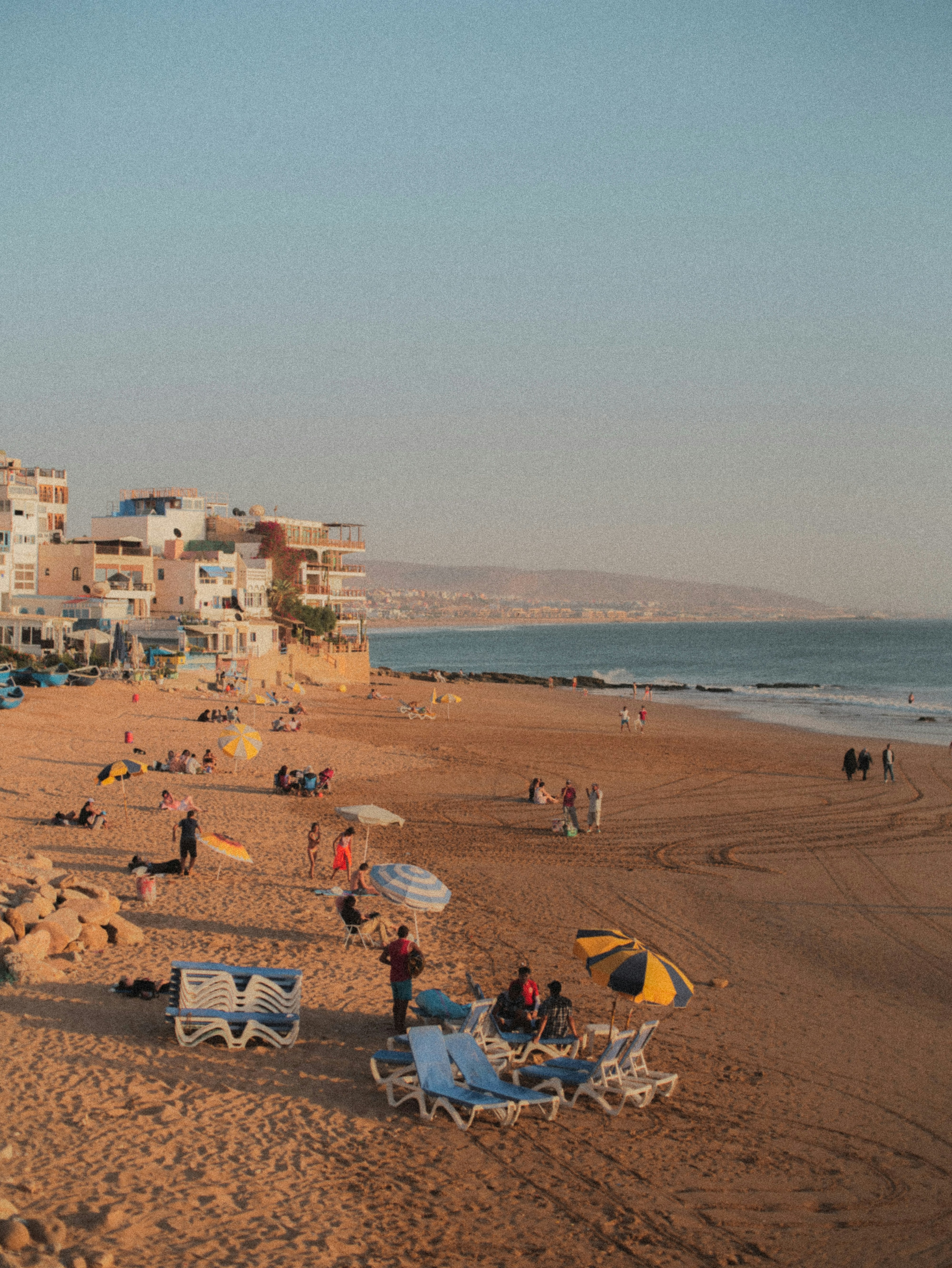 a group of people sitting on top of a sandy beach