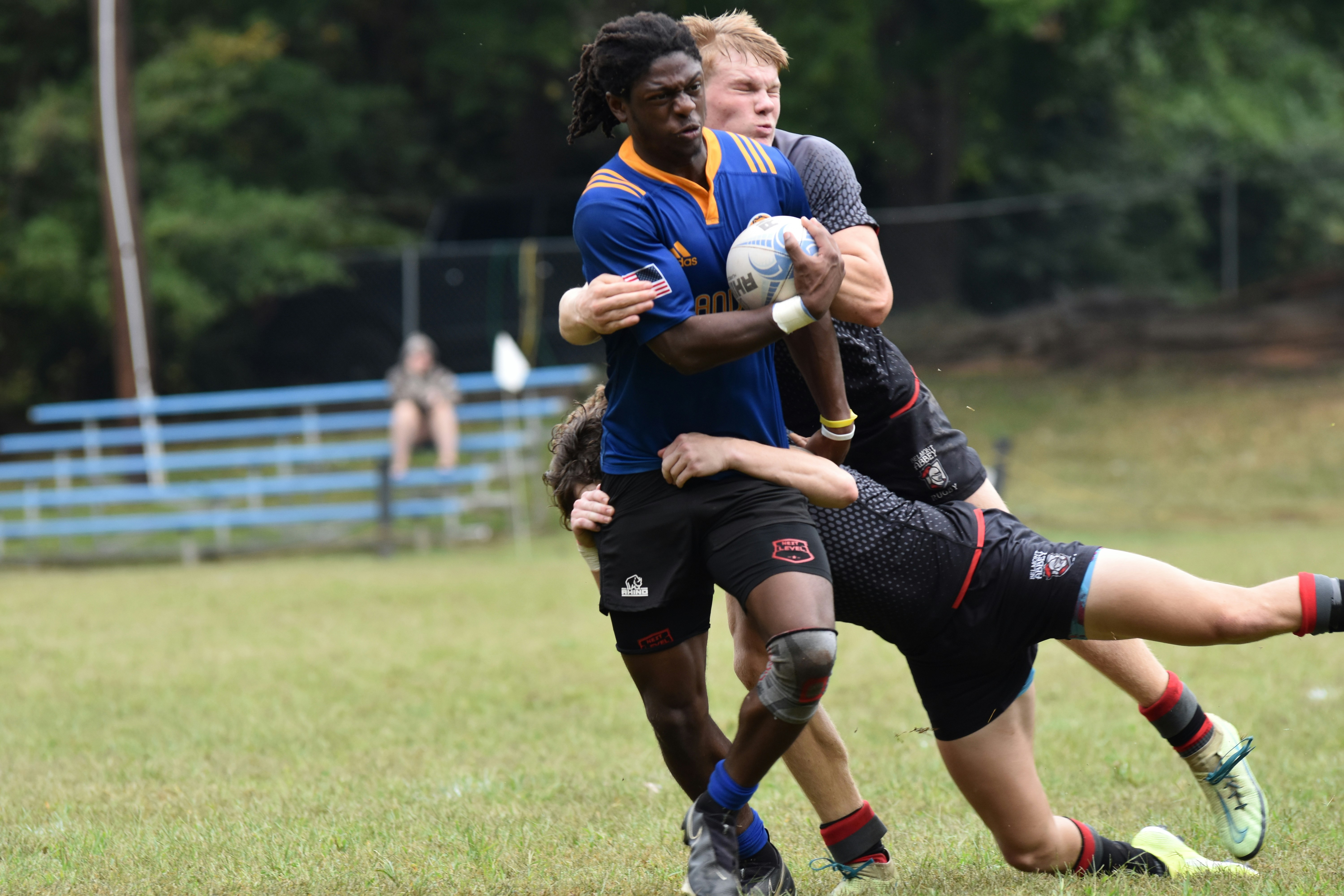 Multiple Belmont Abbey College Players tackle a Lander University player during an Autumn rugby game in Charlotte North Carolina.
