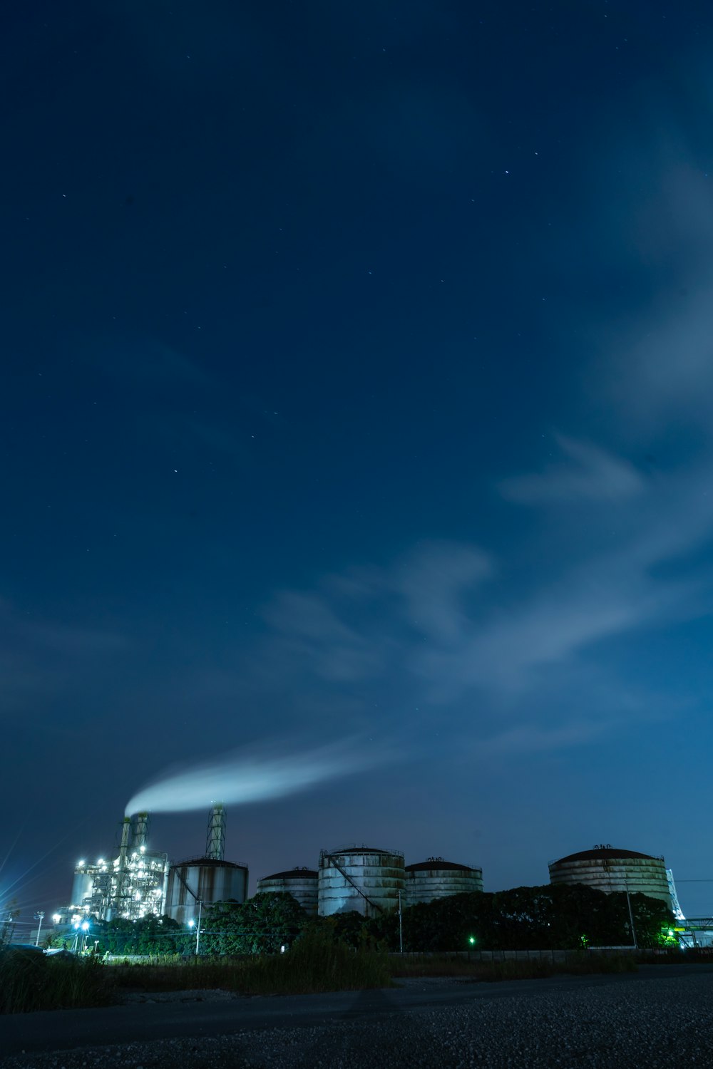 a night time view of a factory with smoke stacks in the background