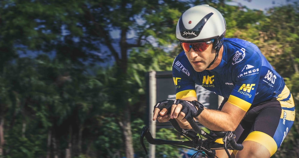 a man riding a bike down a street next to a forest