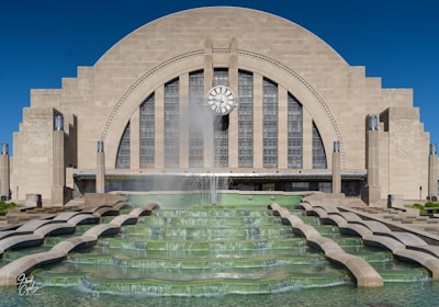 a fountain in front of a building with a clock on it