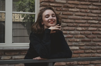 a woman leaning on a rail in front of a brick building