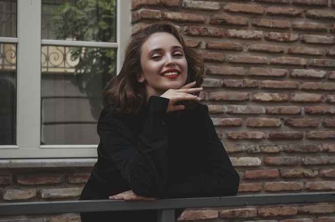 a woman leaning on a rail in front of a brick building