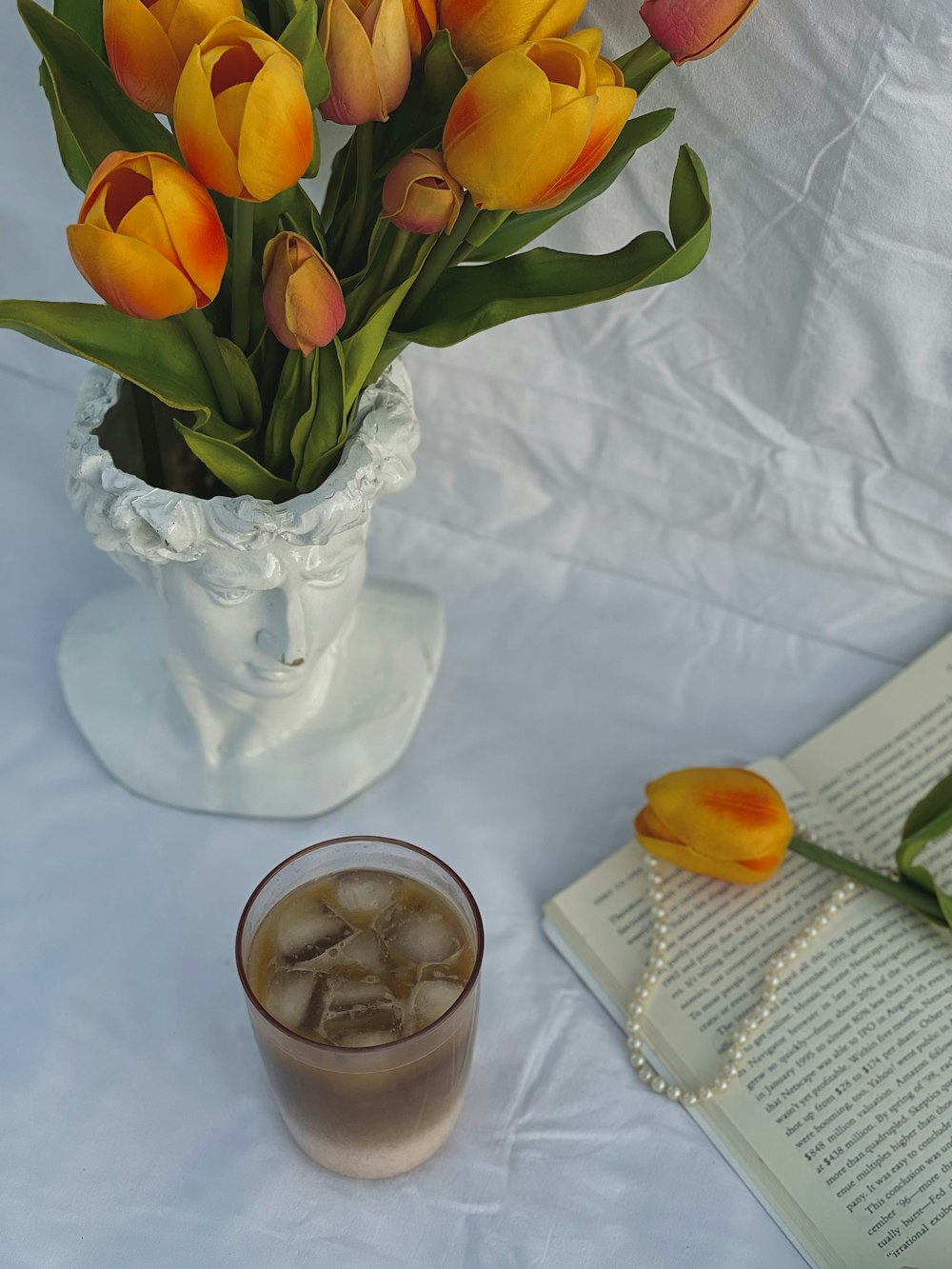 un jarrón de tulipanes y una bebida sobre una mesa