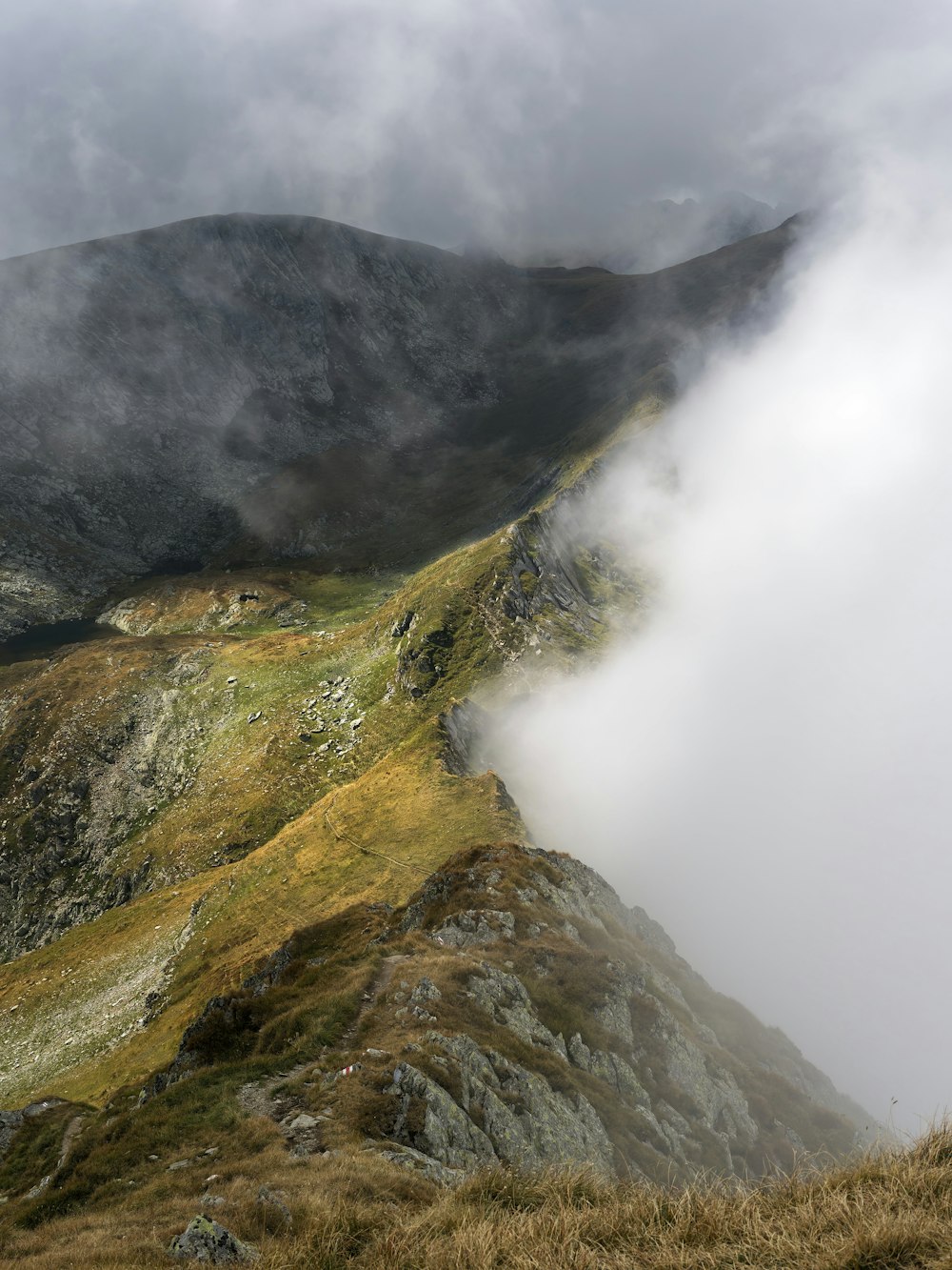 a grassy hill with a few clouds in the sky