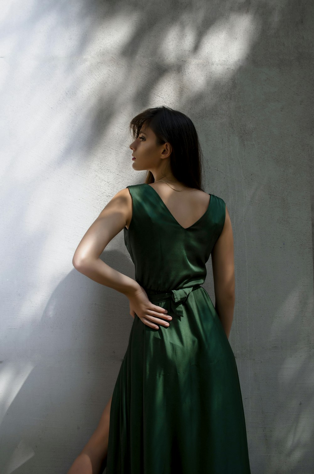 a woman in a green dress standing against a wall