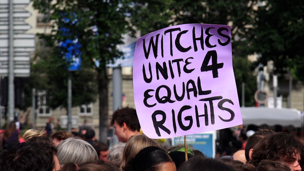 a group of people holding a sign that says witches united 4 equal rights