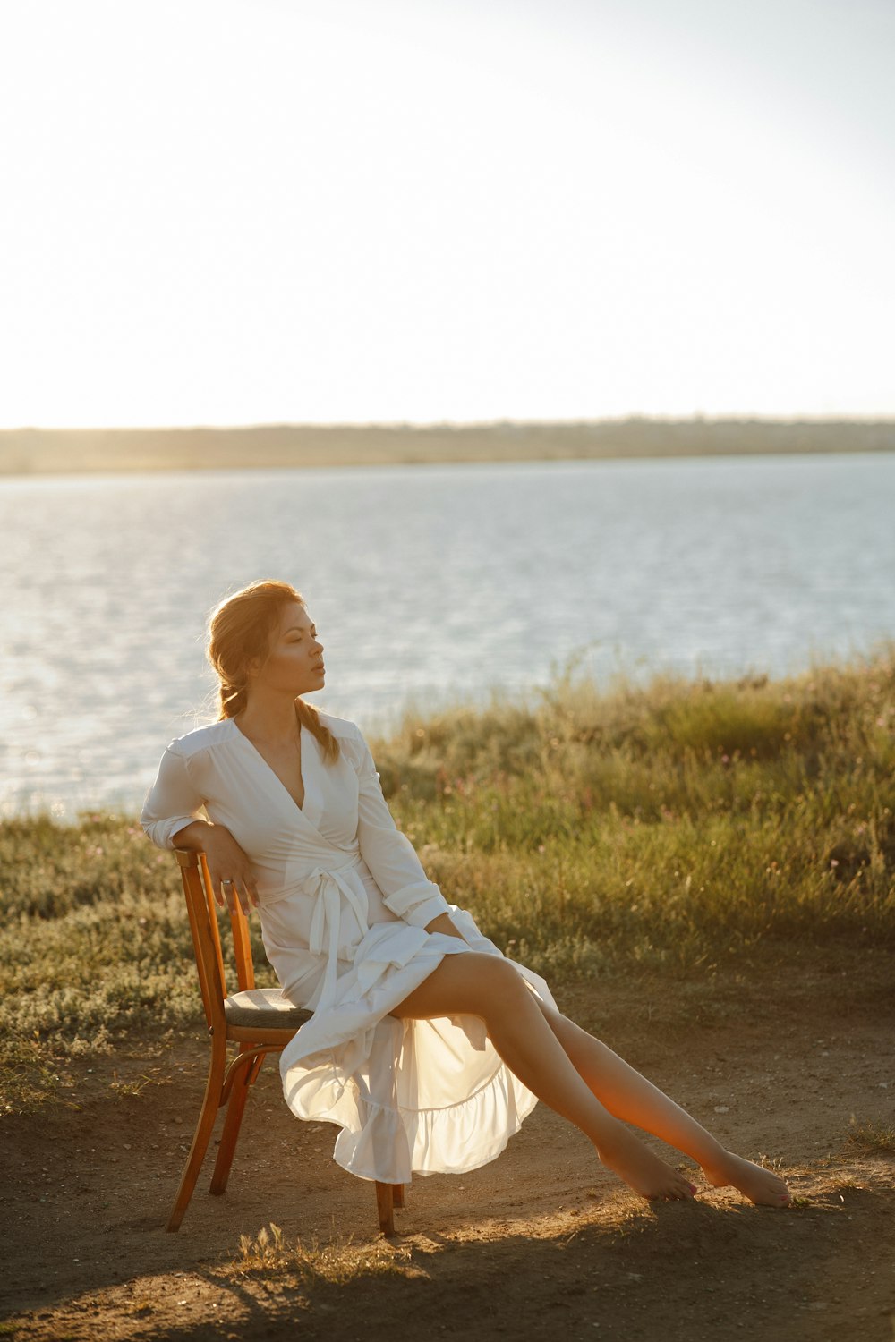 a woman in a white dress sitting on a wooden chair