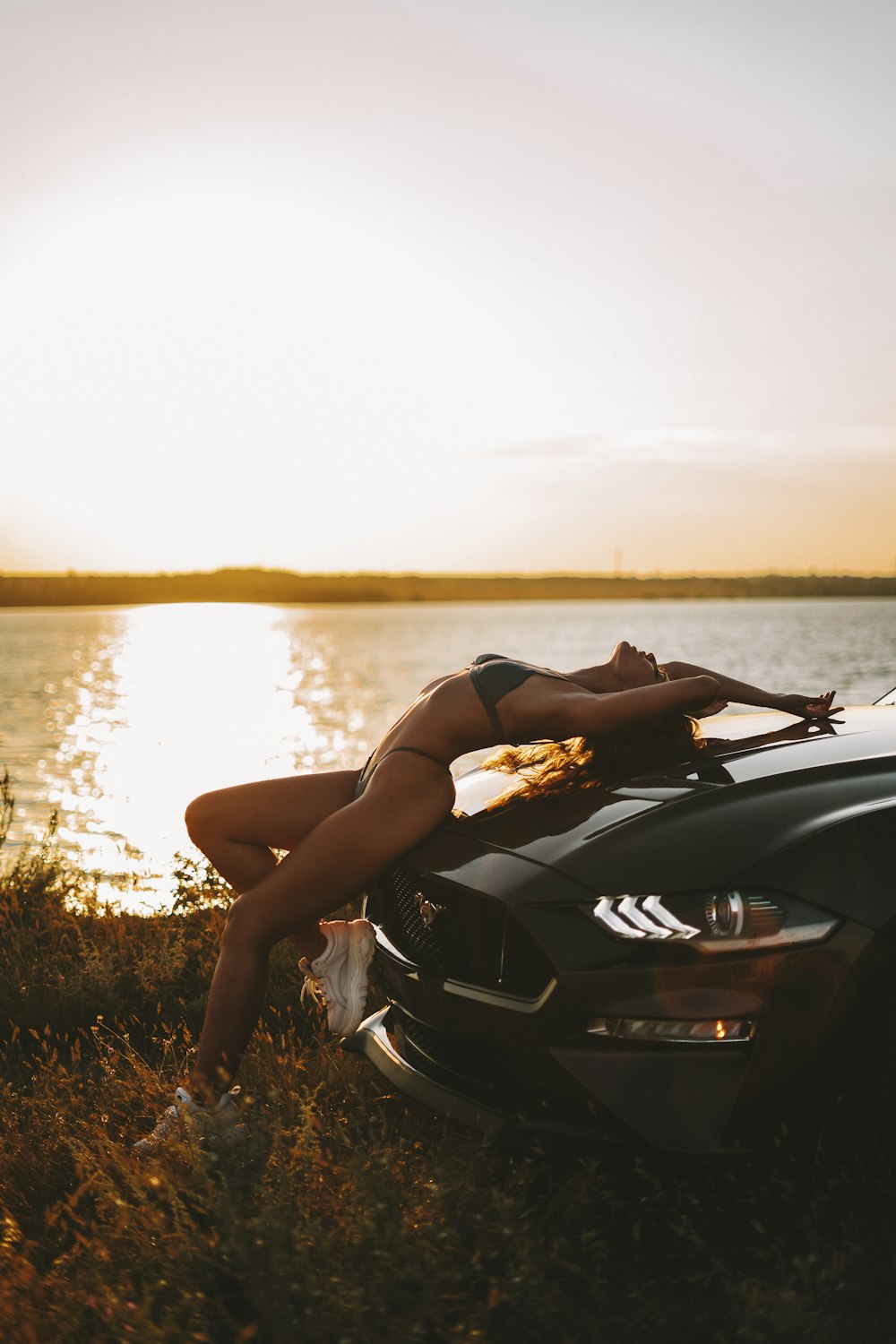 a woman leaning on the hood of a car