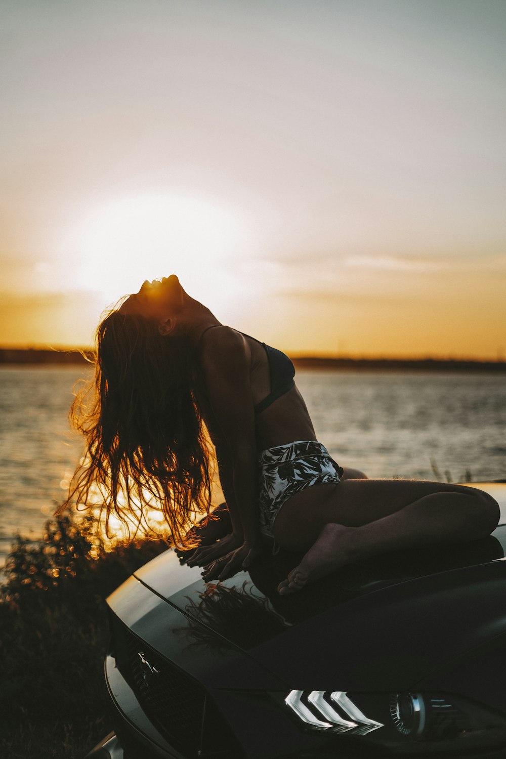 a woman sitting on top of a motorcycle next to a body of water