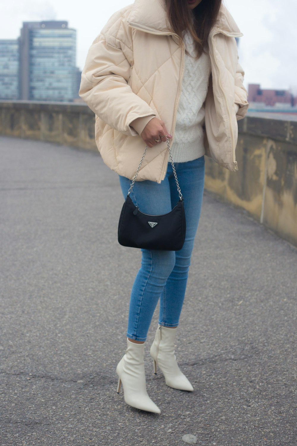 a woman is standing on a bridge with a handbag