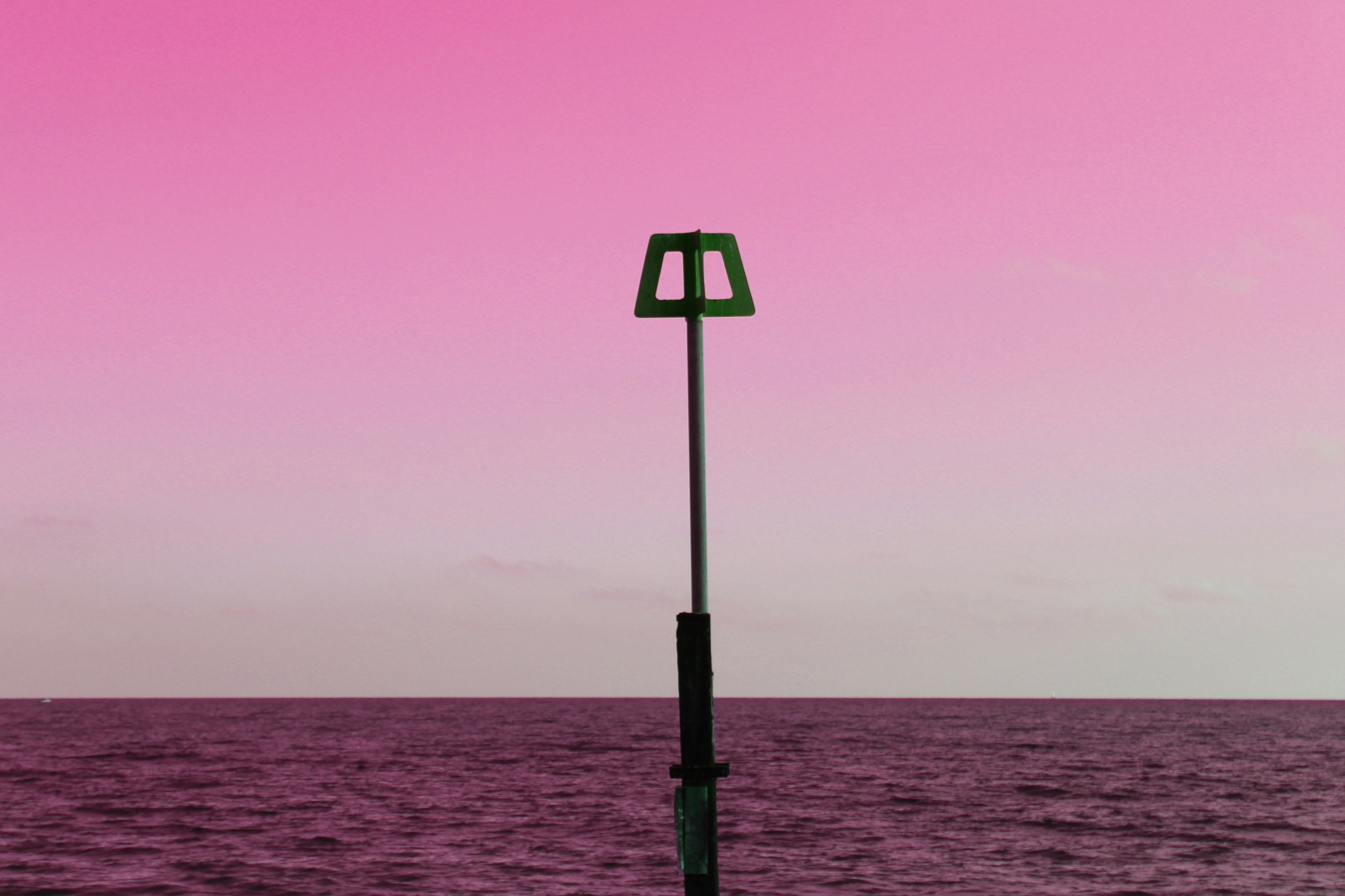 a red light on a pole in the middle of the ocean
