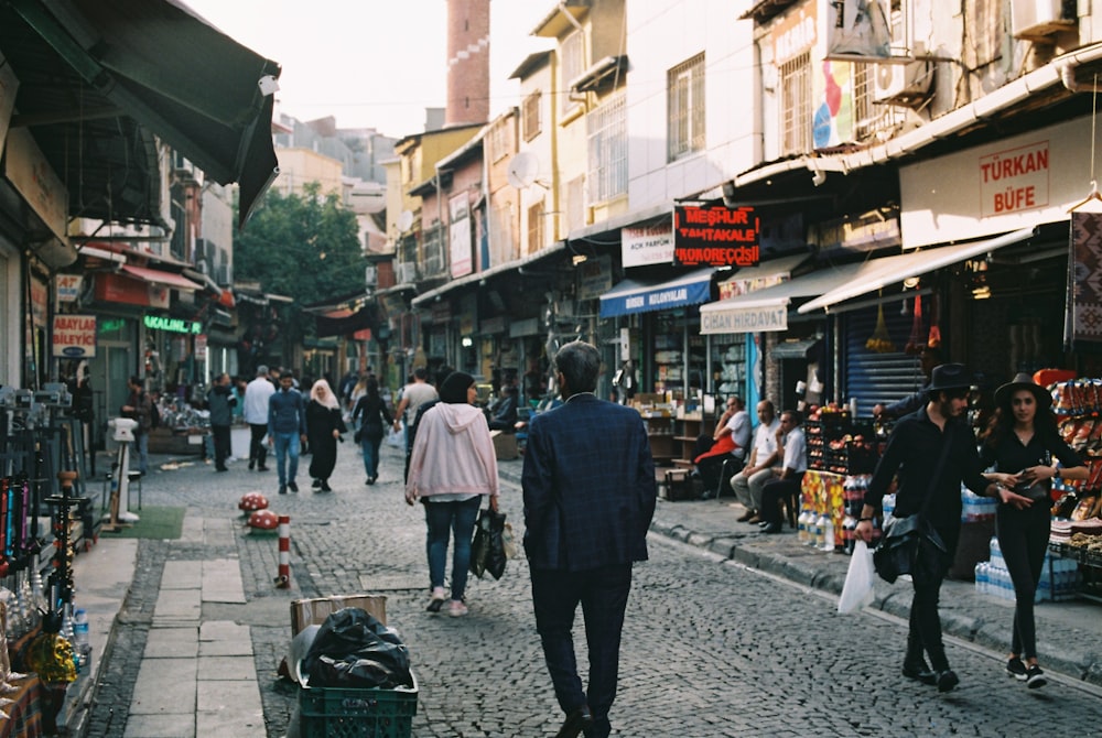 a man in a suit walking down a cobblestone street