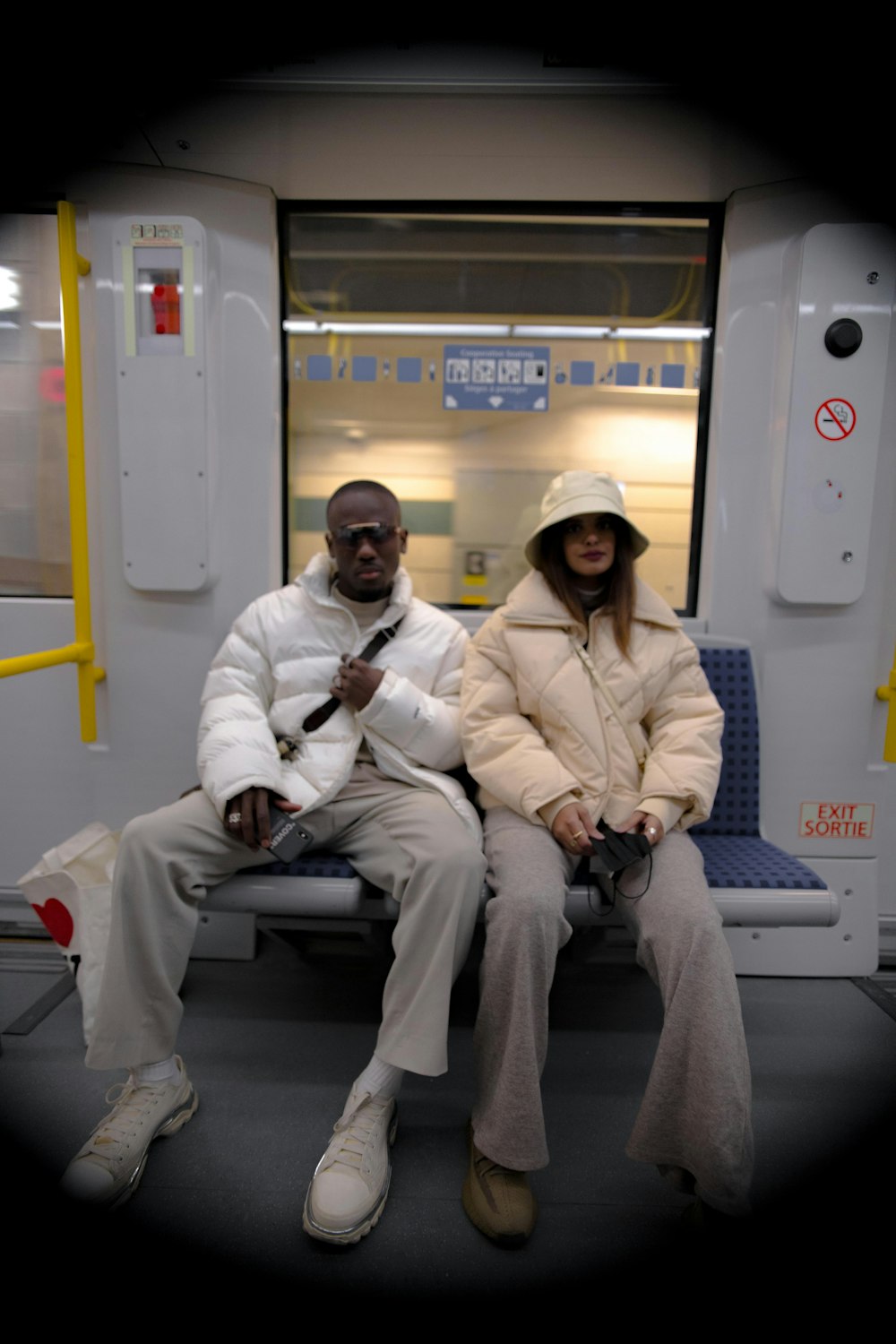 a man and a woman sitting on a subway car