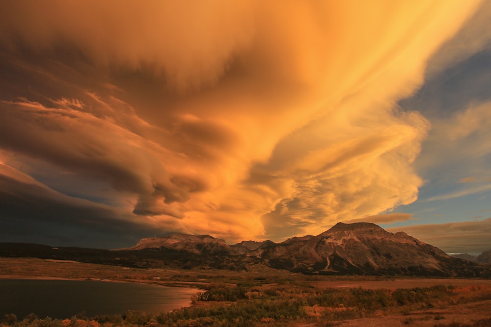 a large cloud is in the sky over a lake